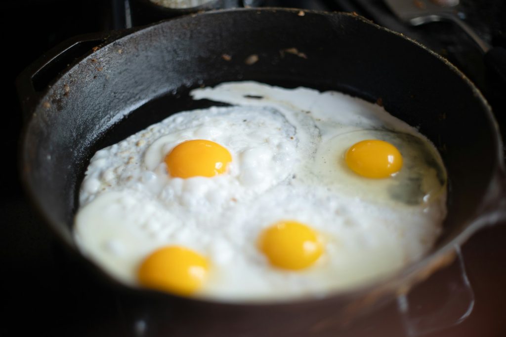 three fried eggs in a frying pan on a stove