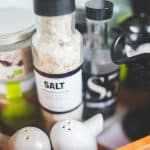Close-up view of various kitchen condiments, featuring salt shaker and other containers.